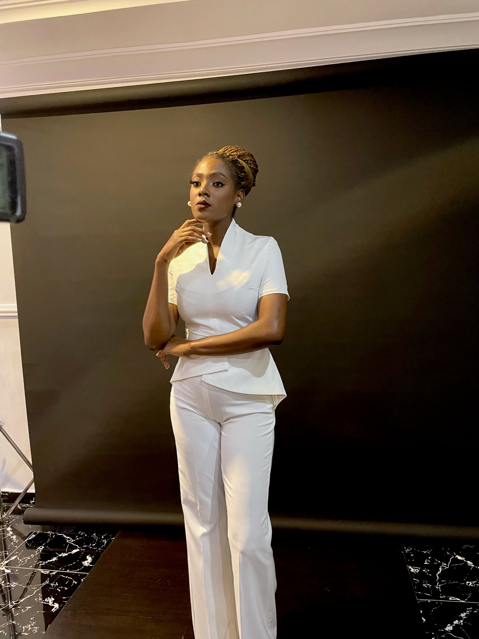 Woman in elegant white tailored suit posing confidently in studio with black backdrop